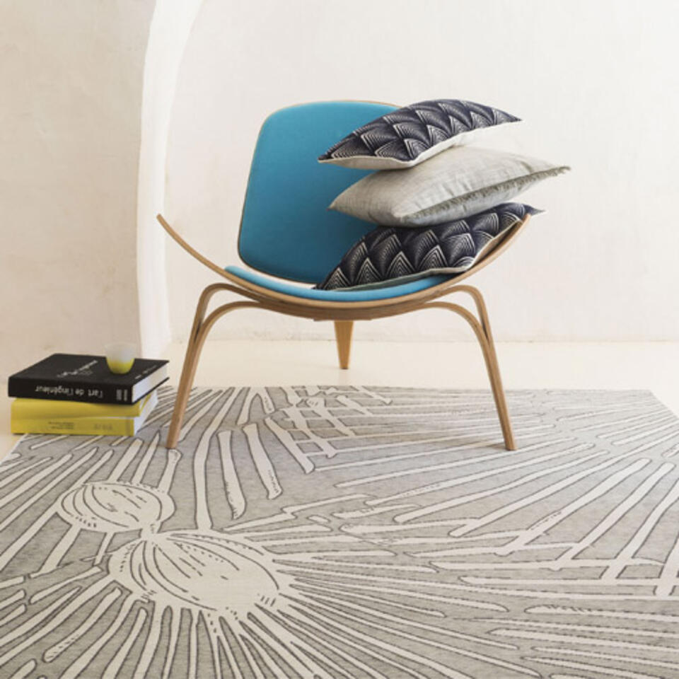 alfombra de salón gris con estampados bajo un sillón